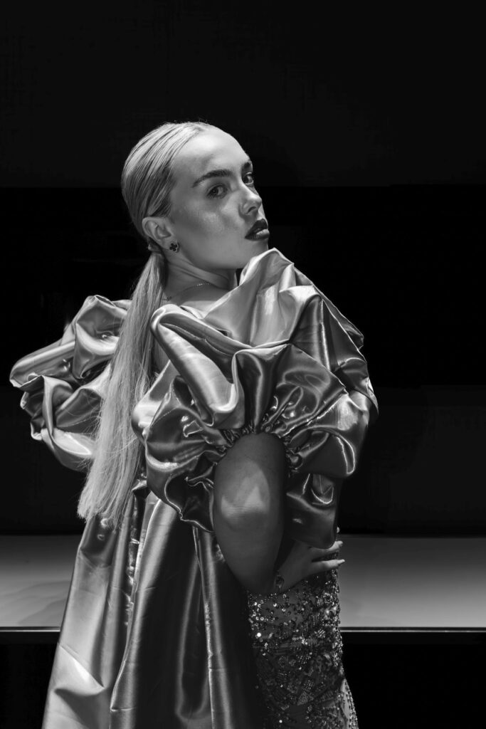 Black and white portrait of a model in an avant-garde gown with sculpted sleeves.