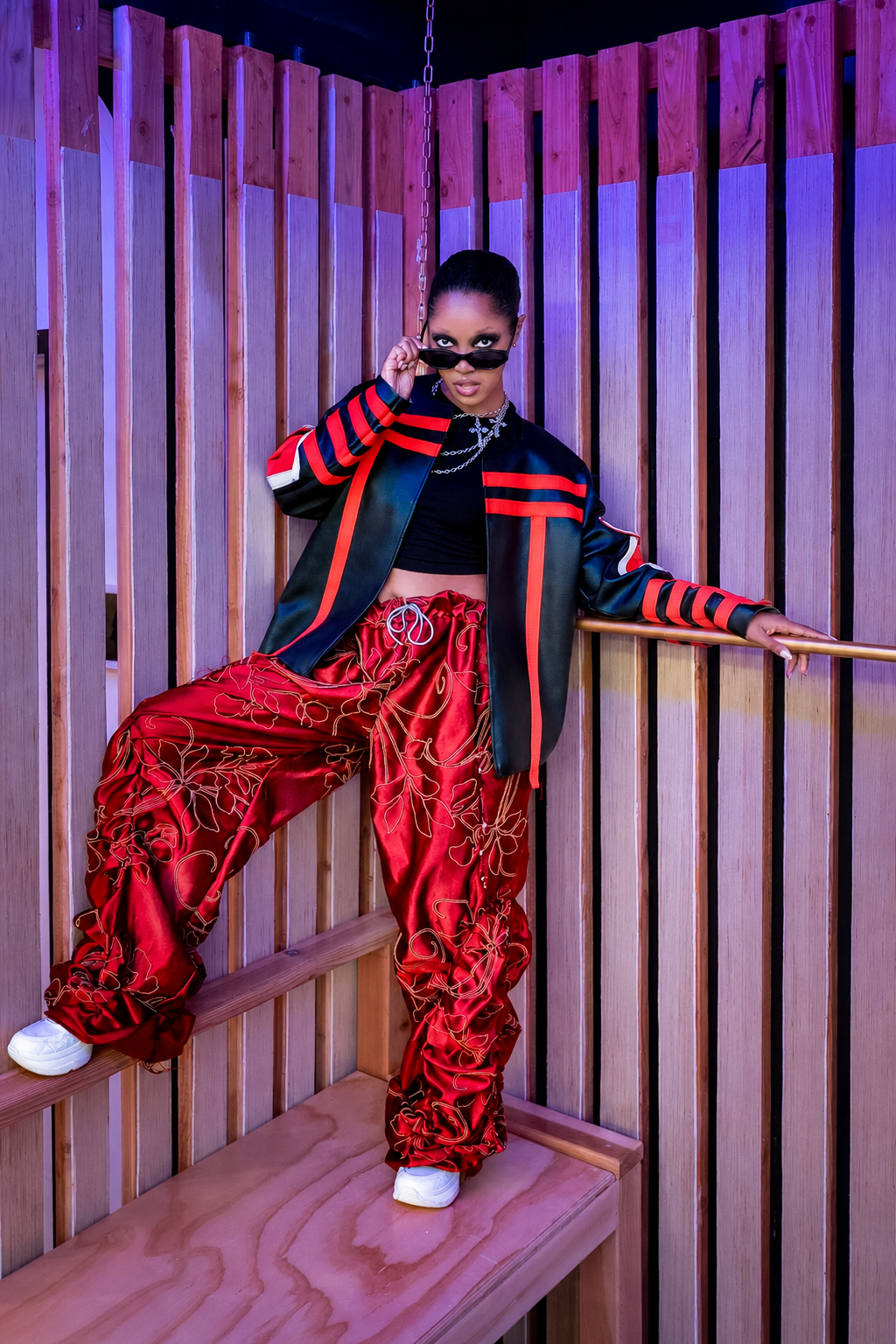 Model wearing a black and red outfit with sunglasses.