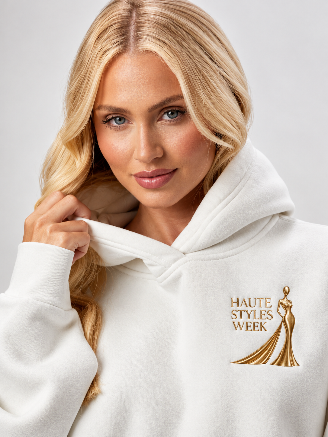 Model wearing the ivory Haute Styles Week hoodie with gold embroidered logo.